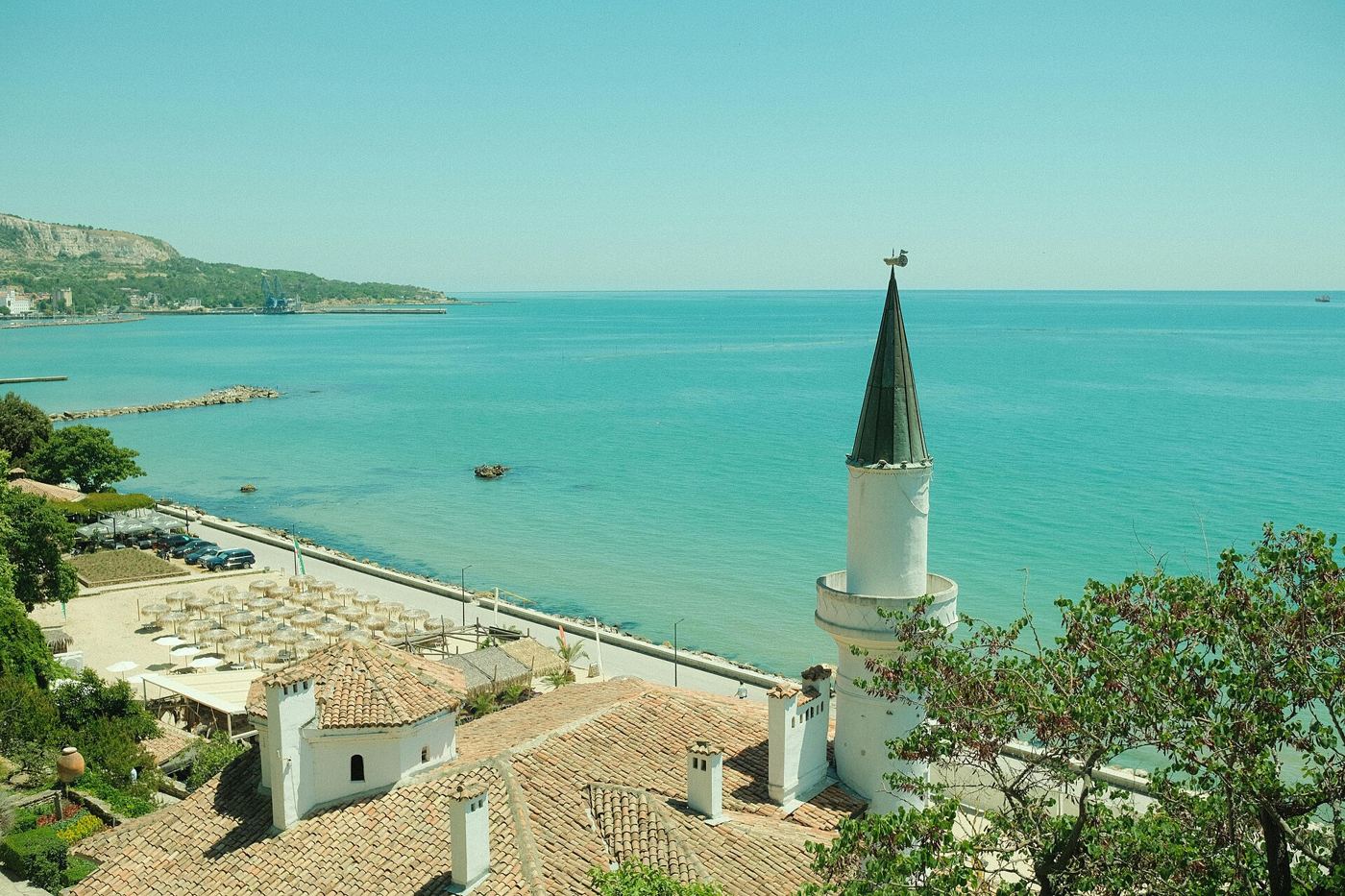 A Mediterranean coastal town and tower under a clear sky